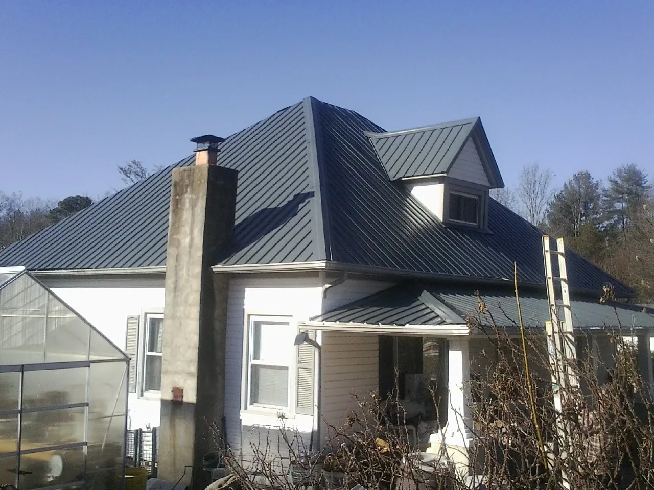 Dark blue standing seam metal roof on a white farmhouse with dormer — Slate & Tile Roof Repair by Roofing Brothers in Wilkeson
