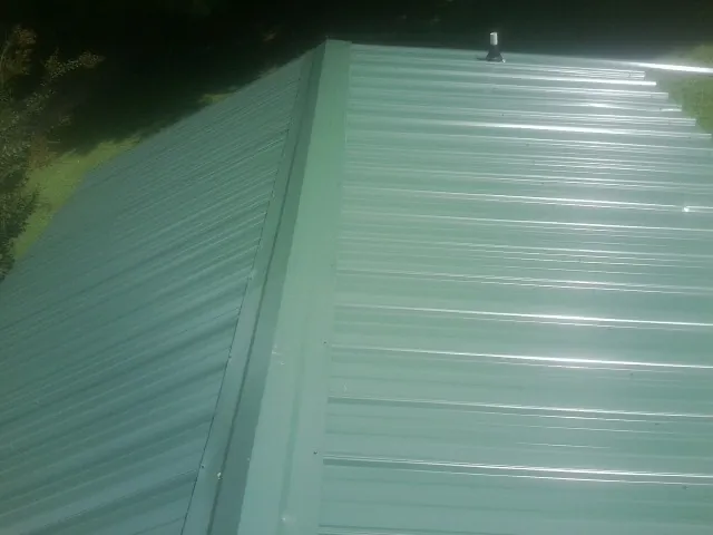 New green metal panels meeting at the ridge of a roof in Wilkeson
