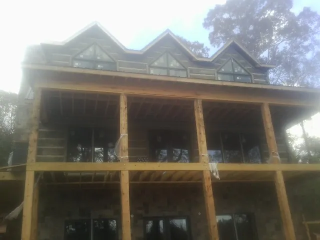 Dormers and porch framing on a large log home under construction — Roof Coating work by our crew in Wilkeson