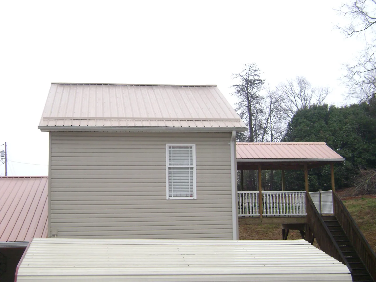 Tan metal roofs on a two story addition and attached porch, from a Roof Replacement job in Wilkeson