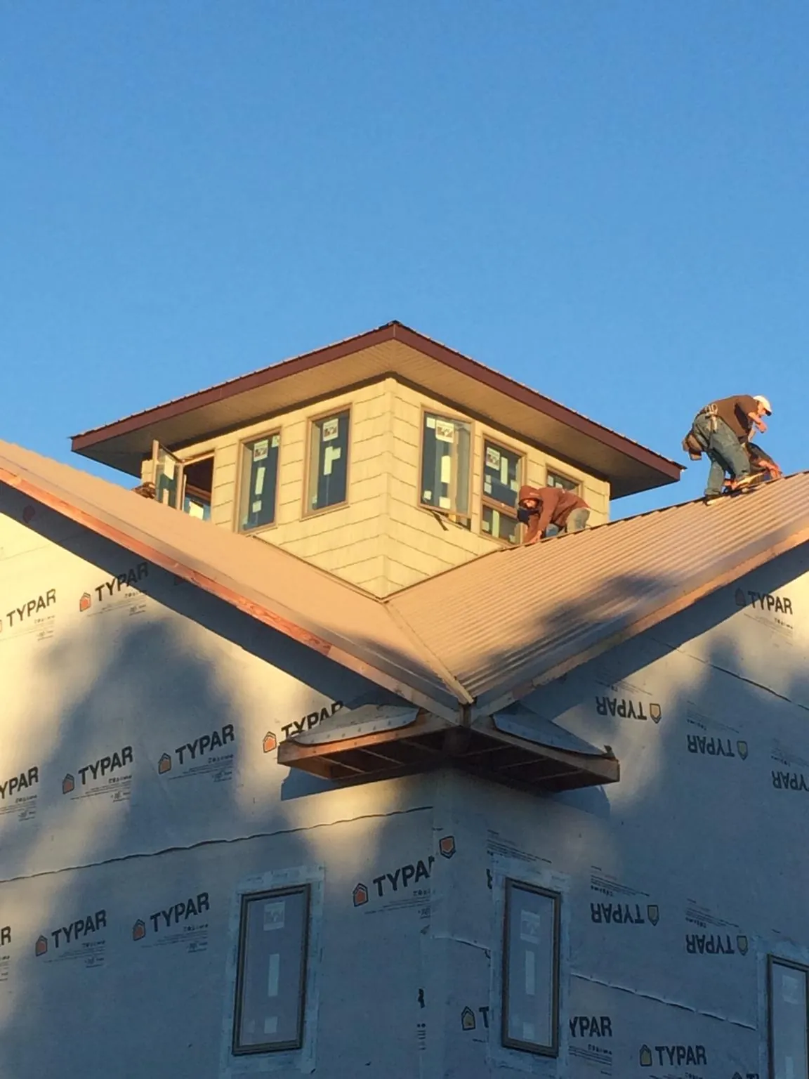 Roofers working around a rooftop cupola on a new metal roof at sunset — Roof Waterproofing in Wilkeson by Roofing Brothers